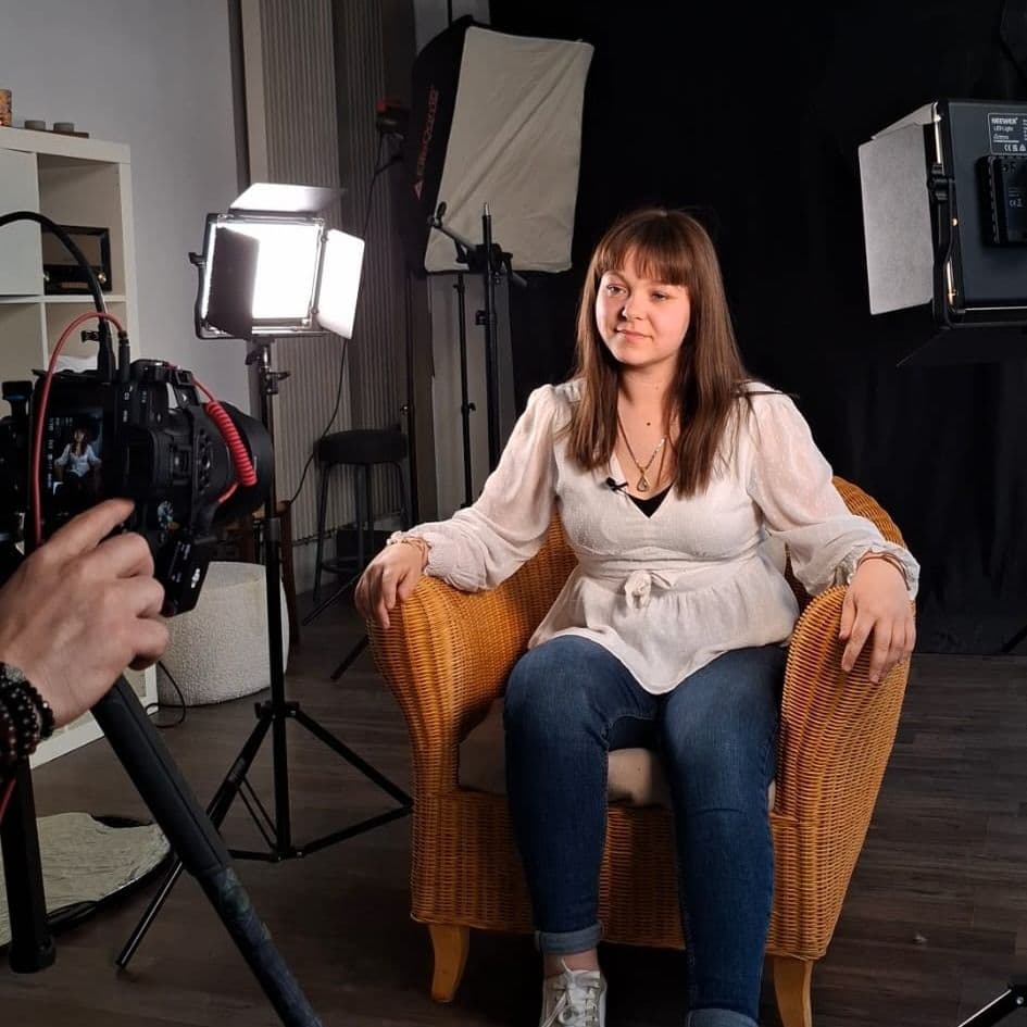 femme assise dans un fauteuil en rotin lors d'un tournage vidéo en studio avec éclairage professionnel